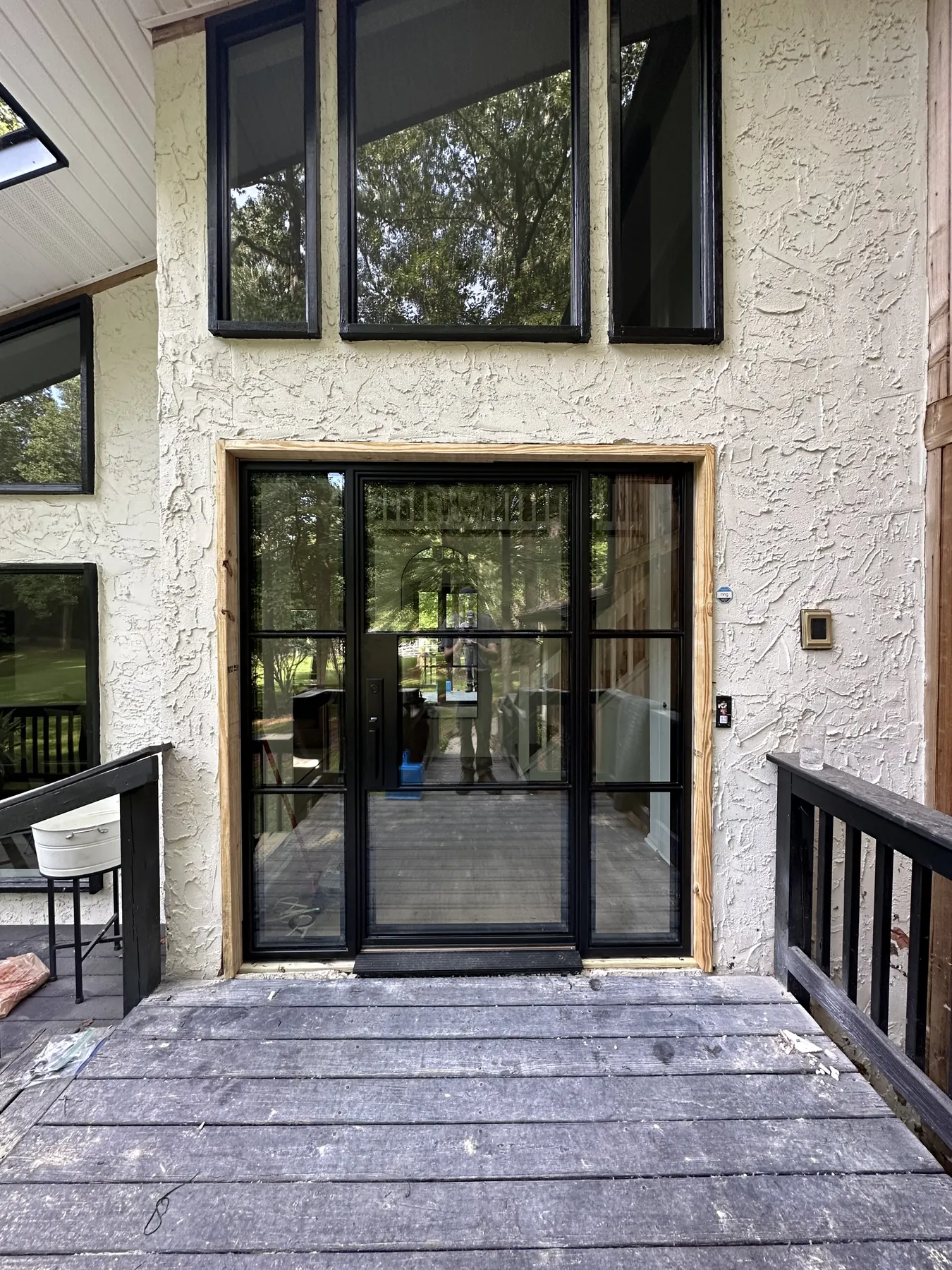 Black steel-and-glass entry doors and upper windows installed on a stucco home